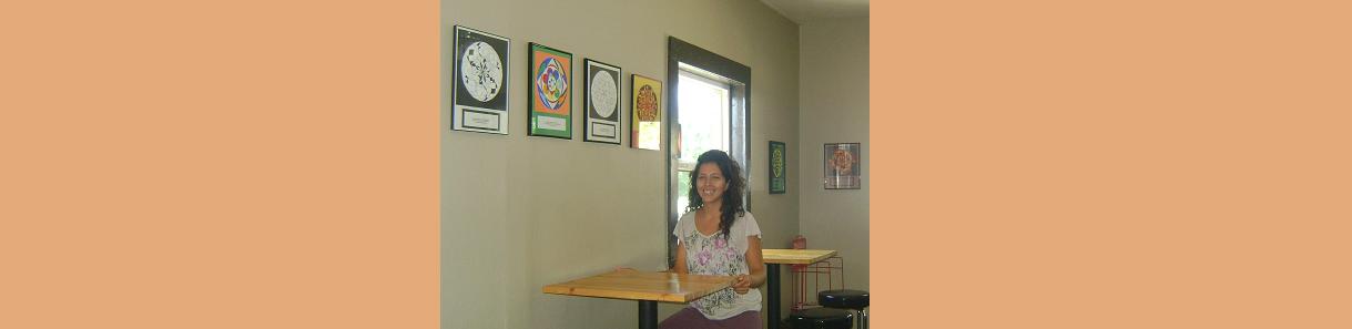 Julieta Corazon is pictured sitting at a table in Creme, the restaurant where her Freedom Meditation pieces are shown on display.
